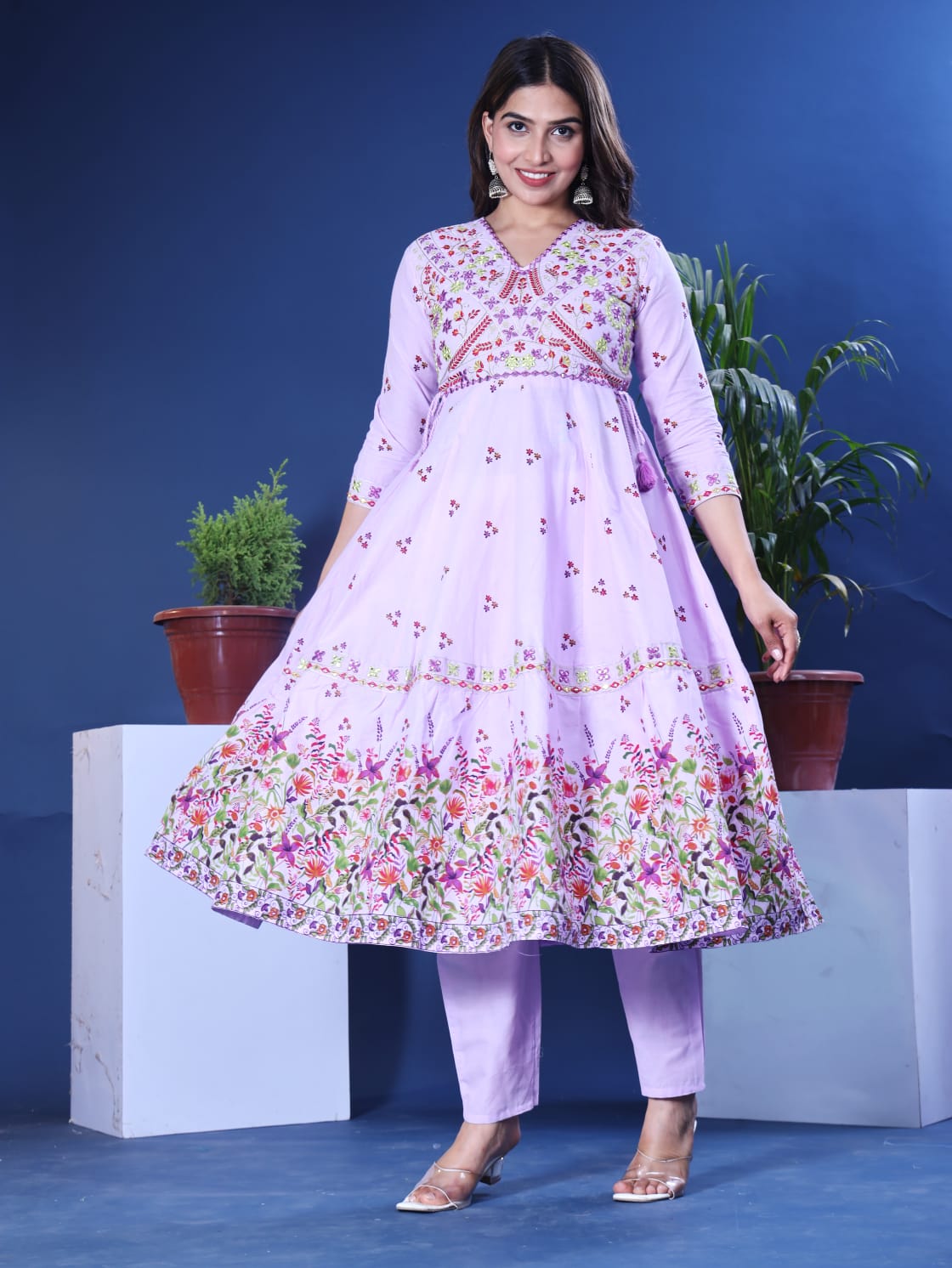 Woman wearing a light purple floral dress and pants against a blue background